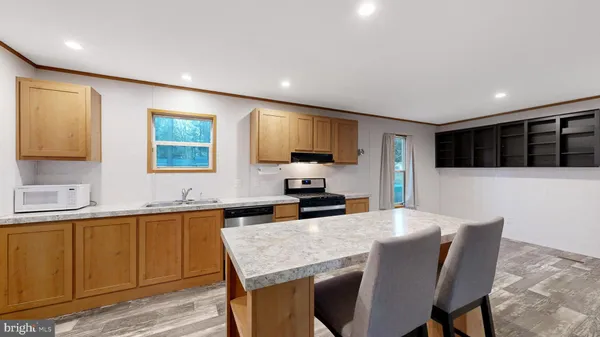 a kitchen with stainless steel appliances granite countertop a sink a stove a microwave a dining table and chairs with wooden floor