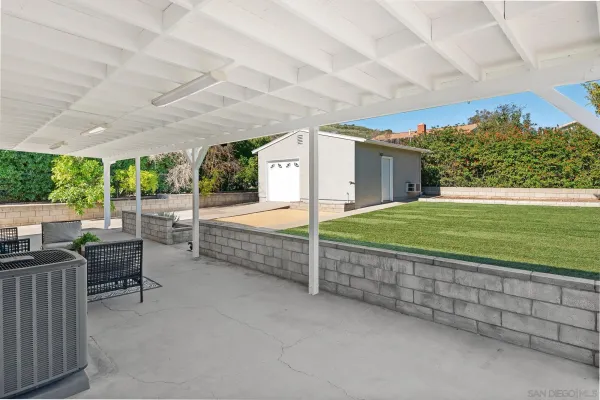 a view of a backyard with couches under an umbrella