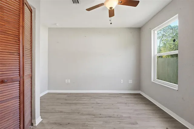 an empty room with a window and a ceiling fan