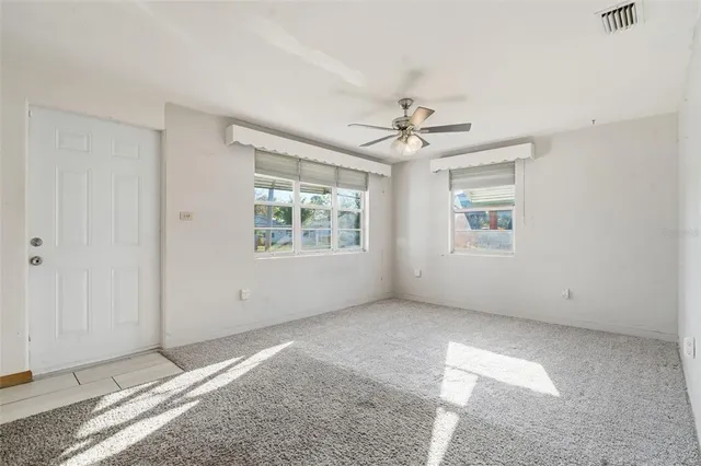 an empty room with windows and ceiling fan