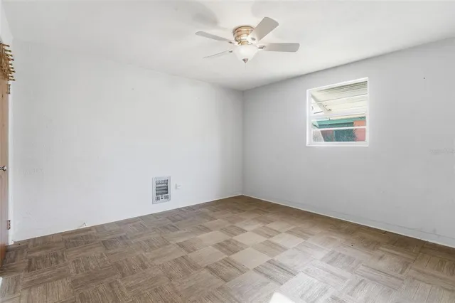 an empty room with a chandelier fan and windows