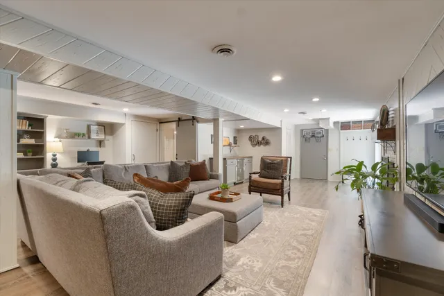 a living room with furniture potted plant and kitchen view