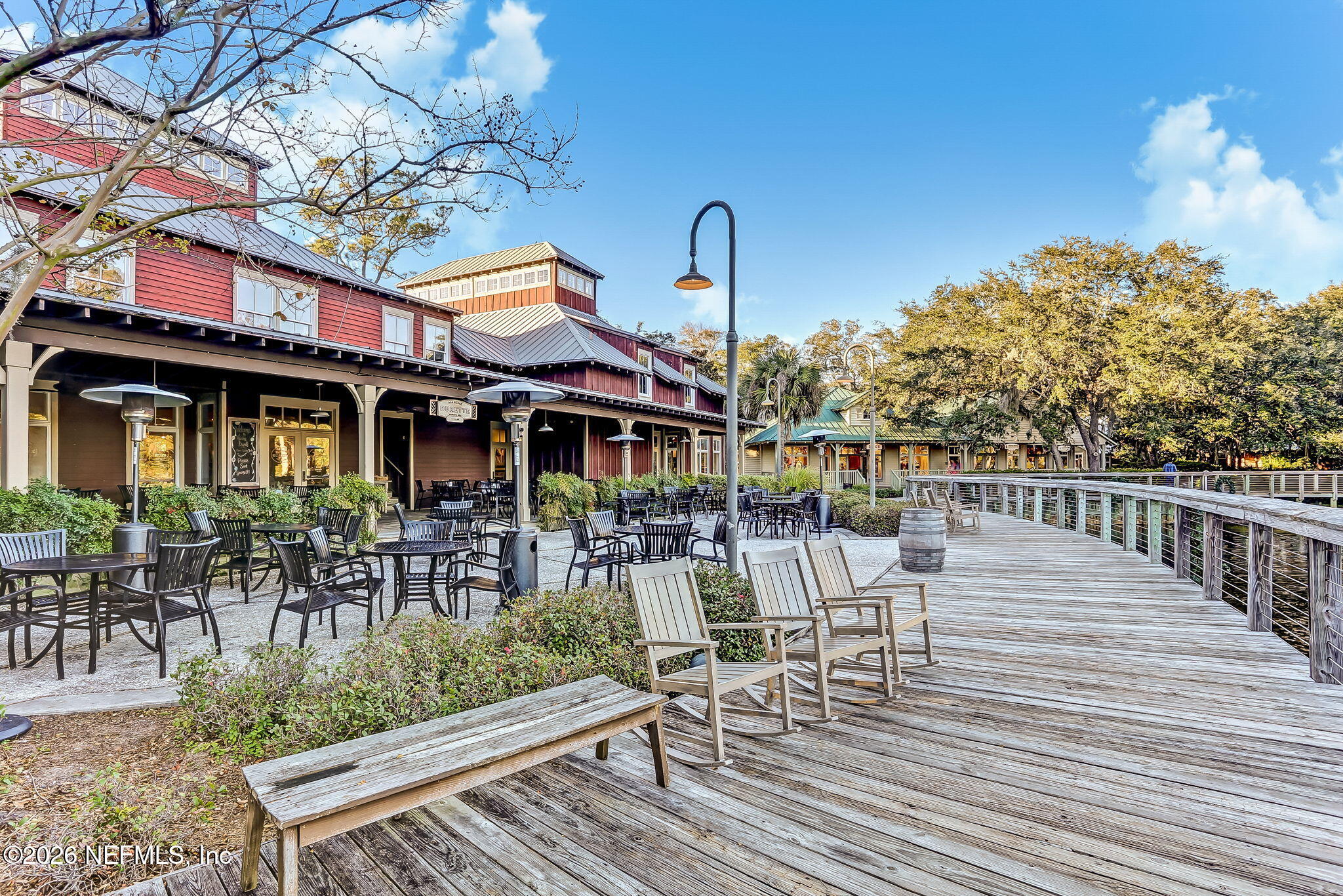 404 Beachside Place Fernandina Beach, FL 32034 - Photo 48 of 96 a view of a patio with table and chairs and potted plants with wooden floor and fence