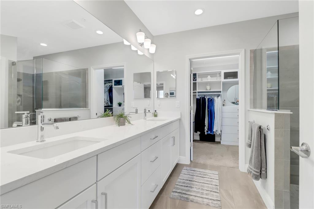 2295 Sawyers Hill Road, Unit 1002 Naples, FL 34120 - Photo 16 of 41 a spacious bathroom with a double vanity sink a large mirror and shower
