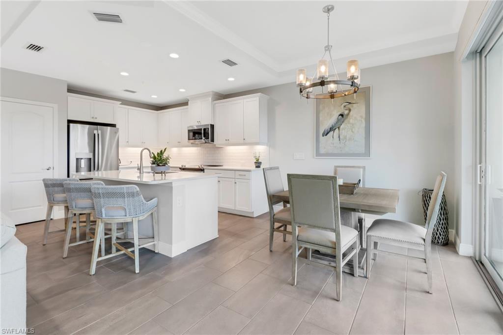 2295 Sawyers Hill Road, Unit 1002 Naples, FL 34120 - Photo 7 of 41 a dining room filled chandelier and kitchen view
