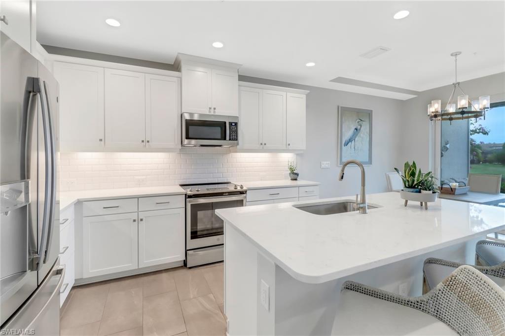 2295 Sawyers Hill Road, Unit 1002 Naples, FL 34120 - Photo 8 of 41 a kitchen with a sink a stove a refrigerator and white cabinets