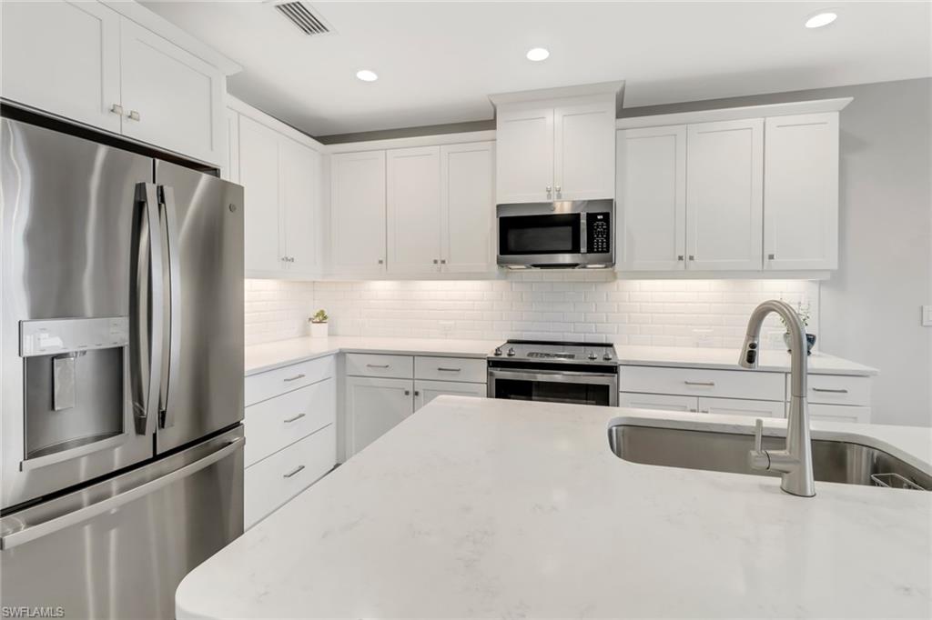 2295 Sawyers Hill Road, Unit 1002 Naples, FL 34120 - Photo 9 of 41 a kitchen with granite countertop a refrigerator stove and microwave