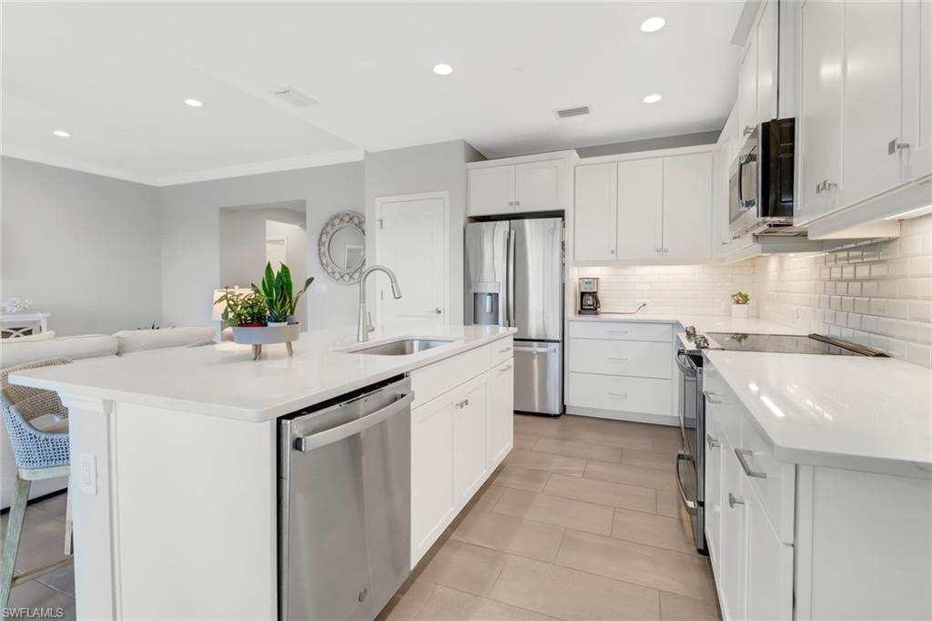 2295 Sawyers Hill Road, Unit 1002 Naples, FL 34120 - Photo 10 of 41 a kitchen with granite countertop a sink and white cabinets
