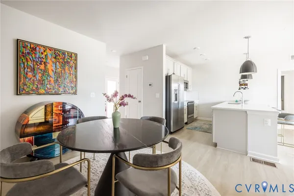 a kitchen with stainless steel appliances kitchen island a refrigerator sink and white cabinets