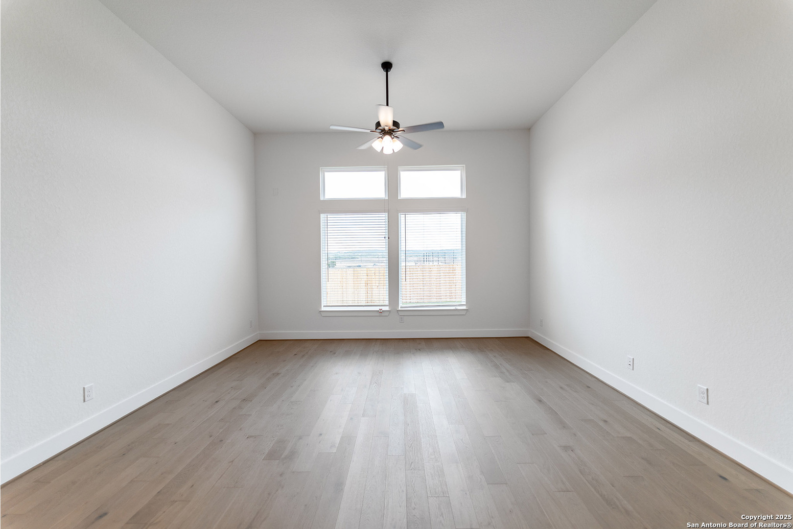 182 Ednie Lane Mico, TX 78056 - Photo 3 of 19 an empty room with wooden floor chandelier fan and windows