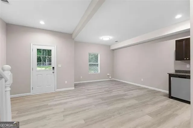 a view of empty room with kitchen and window