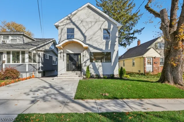 a view of a white house with a big yard and large tree