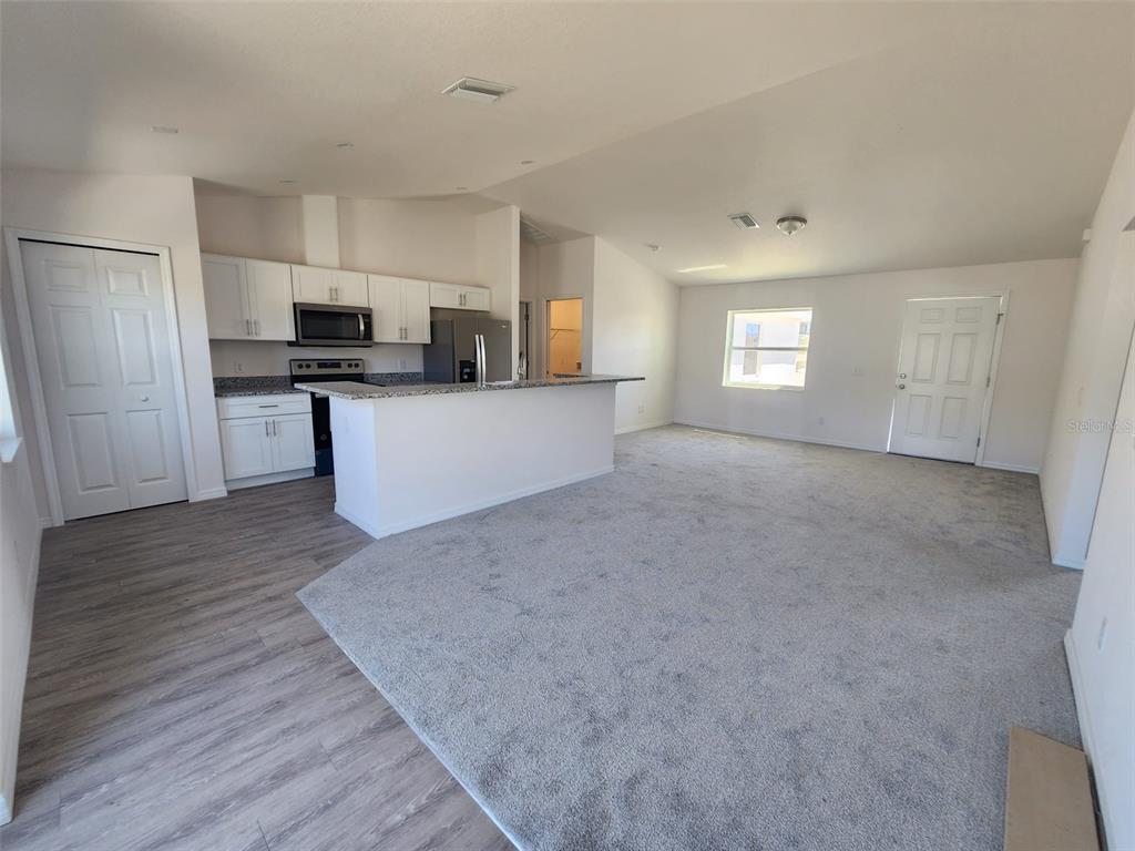 4381 East Ravenna Street Inverness, FL 34453 - Photo 9 of 44 a view of kitchen and empty room with wooden floor and window