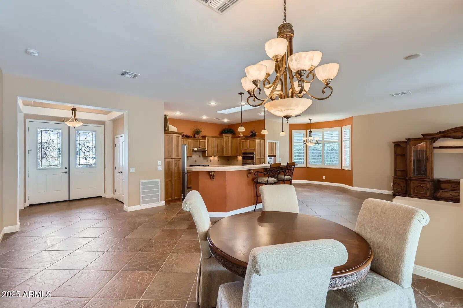 17951 West Sammy Way Surprise, AZ 85374 - Photo 7 of 24 a dining room with wooden floor a chandelier a glass table and chairs