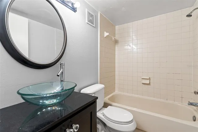 a bathroom with a granite countertop bathtub sink vanity mirror and toilet