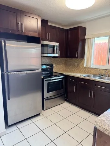 a kitchen with granite countertop a refrigerator and a stove top oven