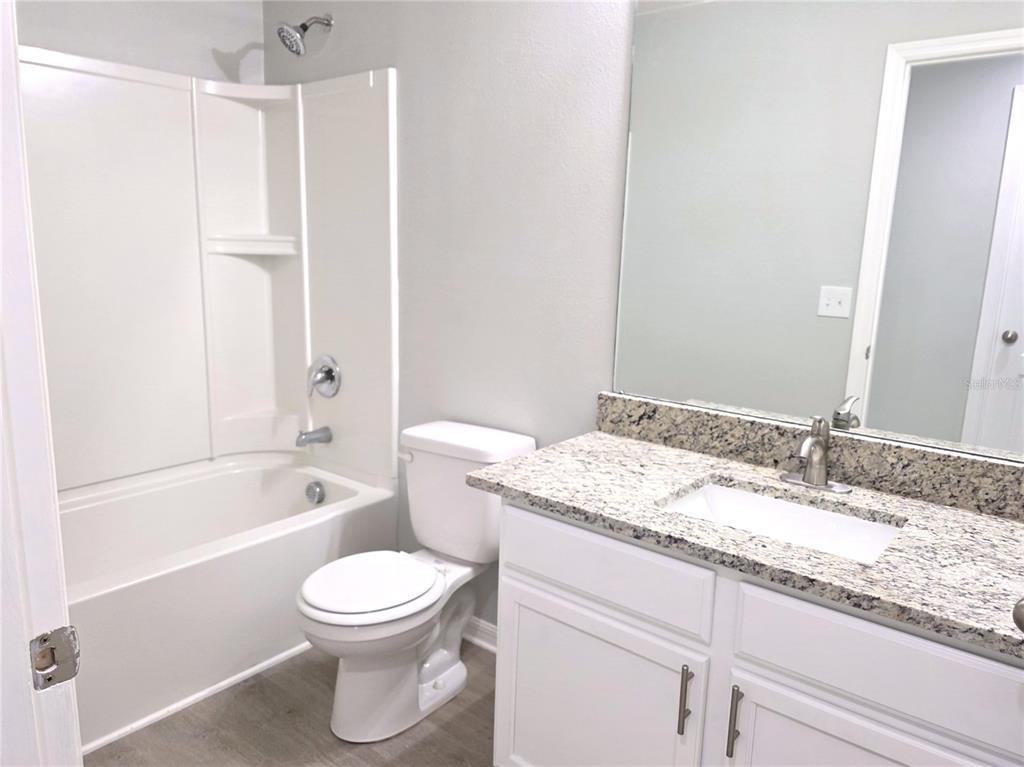 729 Chatham Walk Drive Ruskin, FL 33570 - Photo 11 of 15 a bathroom with a granite countertop sink toilet a large mirror a bathtub and shower