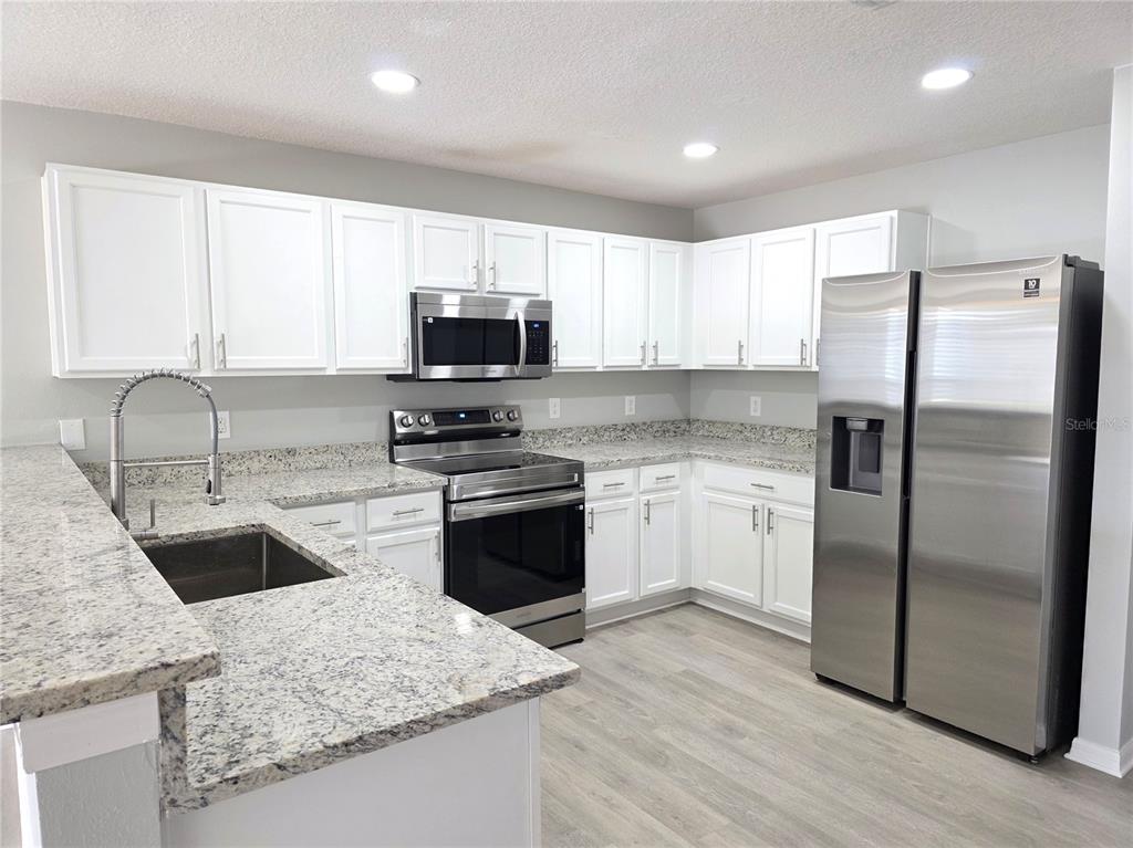 729 Chatham Walk Drive Ruskin, FL 33570 - Photo 5 of 15 a kitchen with stainless steel appliances granite countertop a refrigerator sink and stove