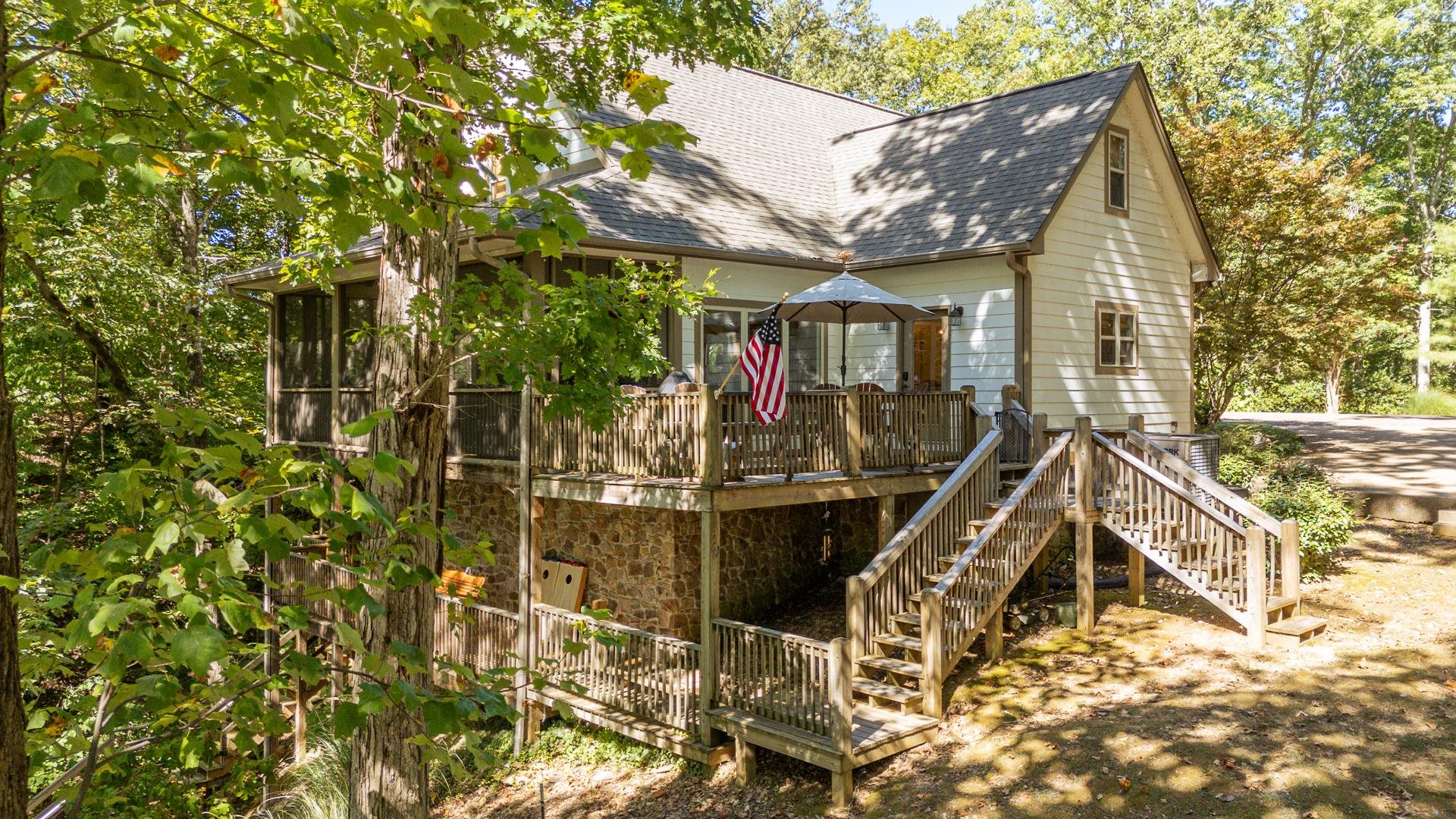 Exterior space featuring stairs, a shingled roof, a wooden deck, and stone siding