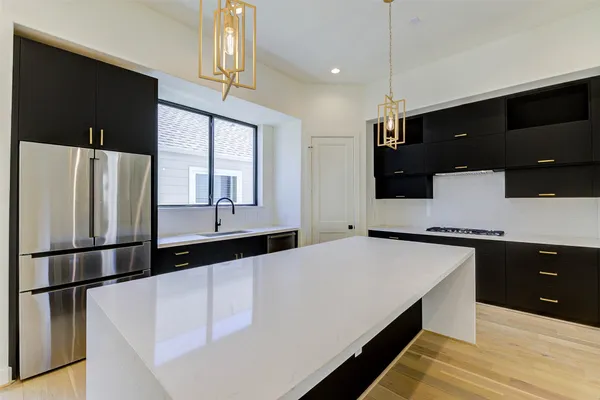 a large kitchen with stainless steel appliances a large counter top a stove and a refrigerator