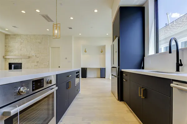 a large kitchen with stainless steel appliances a large counter top a sink a stove and a wooden floors