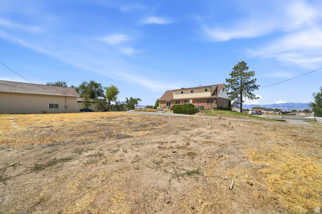 4468 North Droubay Road Tooele, UT 84074 - Photo 37 of 60 Expansive property featuring a two-story residence with brick and siding facade, a mature evergreen tree, and a detached outbuilding