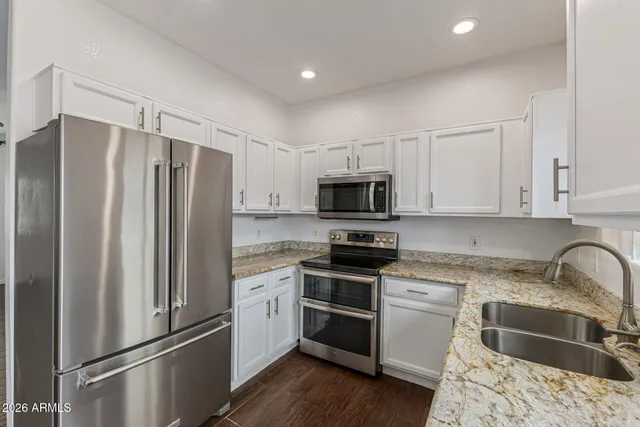 a kitchen with stainless steel appliances granite countertop a refrigerator sink and stove