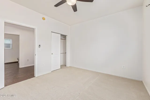an empty room with ceiling fan and window