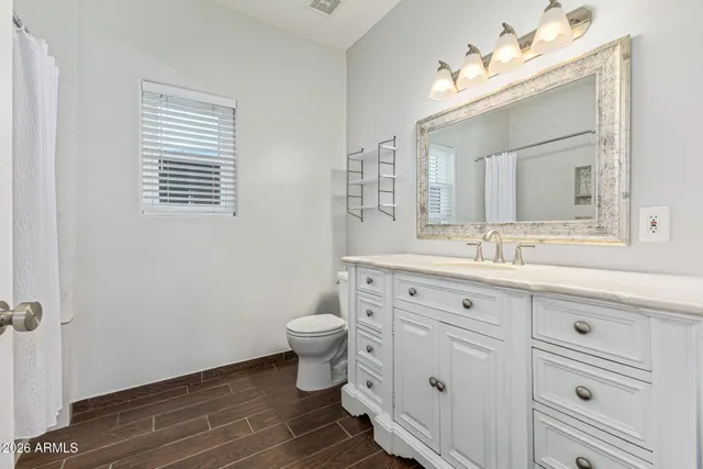 a bathroom with a toilet a sink a mirror and a window