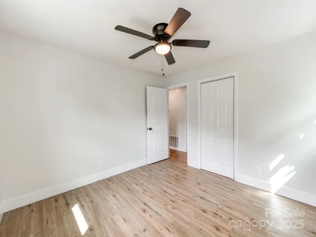 an empty room with wooden floor and ceiling fan