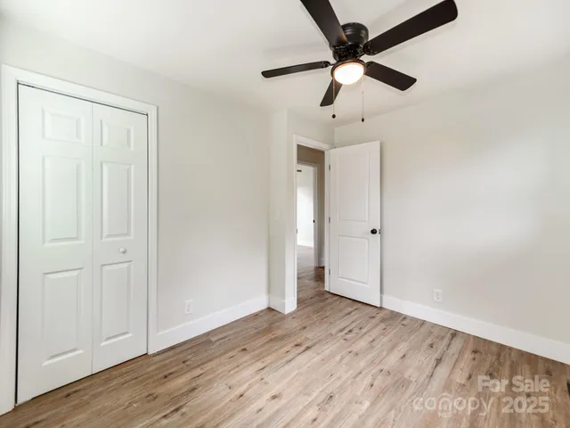 an empty room with wooden floor ceiling fan and windows