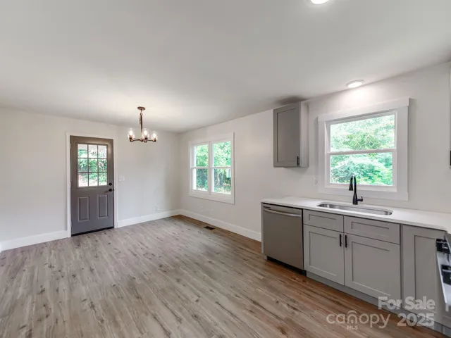 a view of a kitchen sink and dishwasher with wooden floor