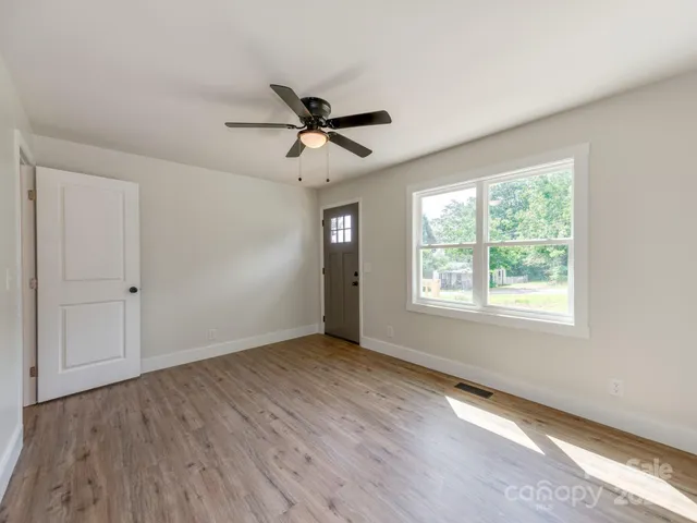 a view of empty room with wooden floor and fan