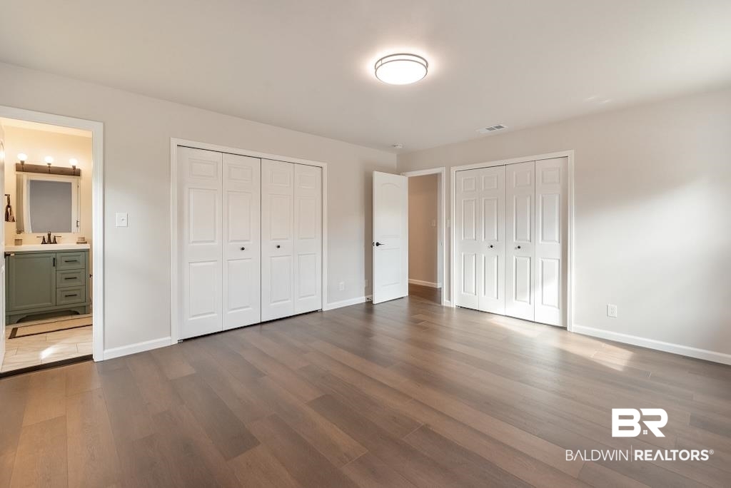 554 Stuart Street Daphne, AL 36526 - Photo 11 of 49 Unfurnished bedroom with ensuite bath, multiple closets, dark hardwood / wood-style flooring, and sink