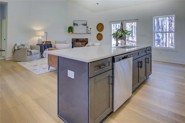 a kitchen with kitchen island a counter top space a sink a stove and wooden floor