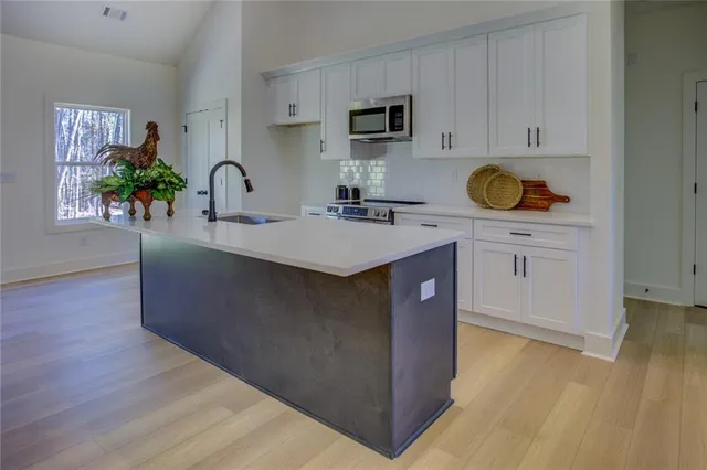 a kitchen with stainless steel appliances granite countertop a sink a stove and a wooden floors