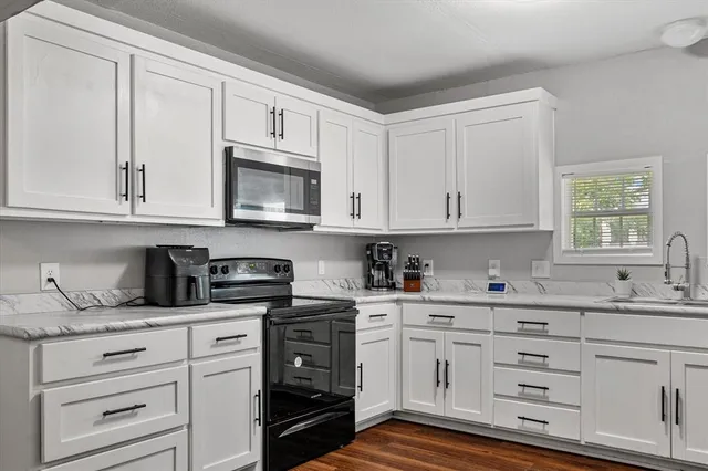 a kitchen with white cabinets and sink