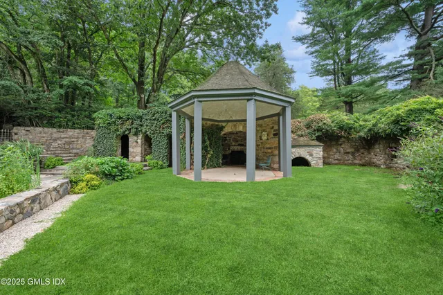 a view of a big house with a big yard and large trees