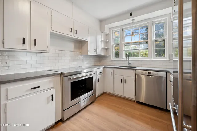 a white kitchen with granite countertop a stove top oven sink and cabinets