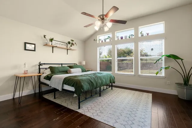 a bedroom with a bed and a large window with wooden floor