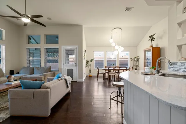 a living room with furniture a chandelier and wooden floor