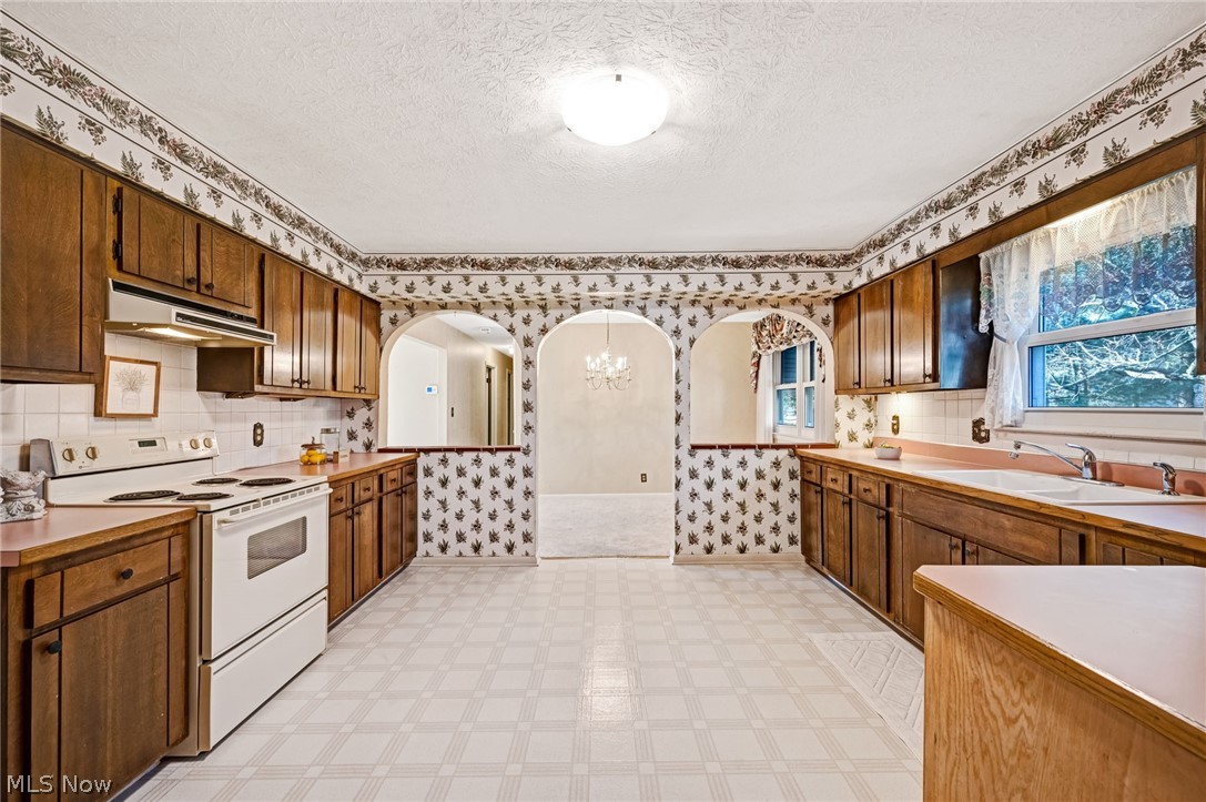 6452 Carsten Road Medina, OH 44256 - Photo 9 of 41 Kitchen with a textured ceiling, tasteful backsplash, electric stove, a notable chandelier, and sink