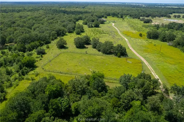an aerial view of residential houses with outdoor space and trees