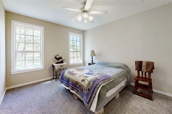 a bedroom with a bed a chair and a large window