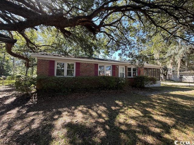 Ranch-style house with a sunroom, brick siding, and a front lawn
