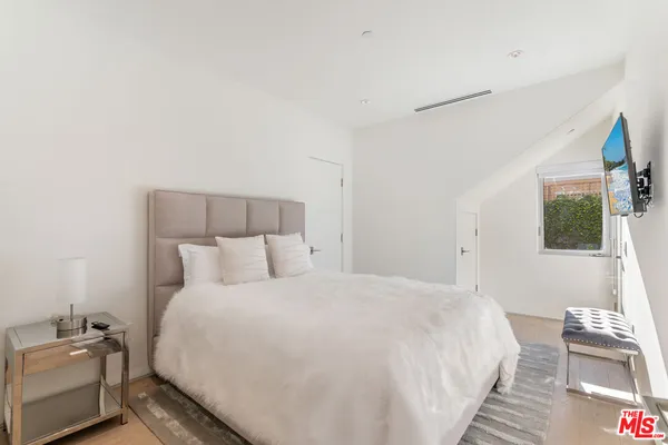 a bedroom with a bed wooden floor and a large window