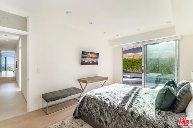 a bedroom with a bed wooden floor and a large window