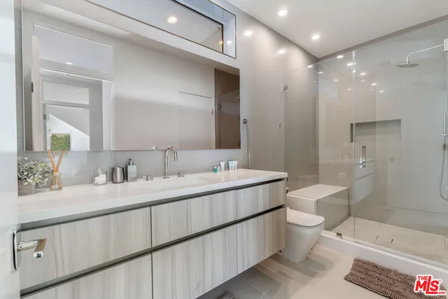 a bathroom with a double vanity sink toilet mirror and bathtub
