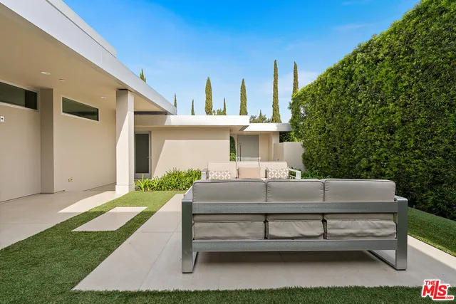 a view of a patio with couches table and chairs under an umbrella