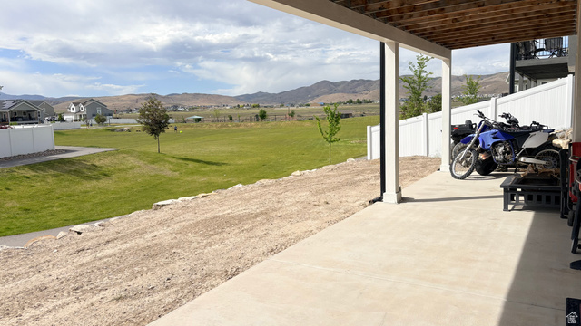 7889 Bristlecone Road Eagle Mountain, UT 84005 - Photo 41 of 42 Covered patio with concrete flooring, white vinyl fencing, and a gravel-covered slope